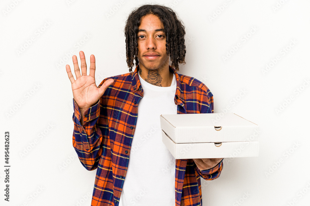 Young African American man holding pizzas isolated on blue background smiling cheerful showing number five with fingers. Young African American man holding pizzas isolated on blue background smiling cheerful showing number five with fingers.