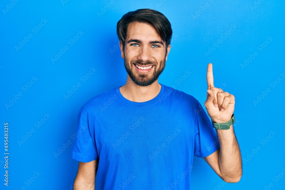 Young hispanic man wearing casual clothes pointing finger up with successful idea. exited and happy. number one. Young hispanic man wearing casual clothes pointing finger up with successful idea. exited and happy. number one.