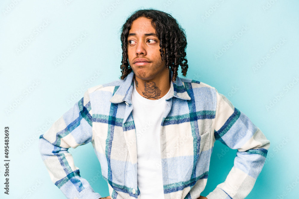 Young African American man isolated on blue background confused, feels doubtful and unsure. Young African American man isolated on blue background confused, feels doubtful and unsure.