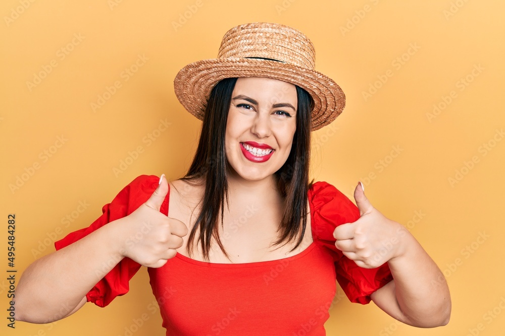 Young hispanic woman wearing summer hat success sign doing positive gesture with hand, thumbs up smiling and happy. cheerful expression and winner gesture. Young hispanic woman wearing summer hat success sign doing positive gesture with hand, thumbs up smiling and happy. cheerful expression and winner gesture.