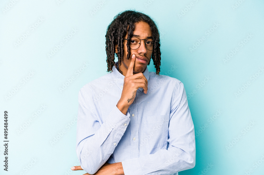 Young African American man isolated on blue background contemplating, planning a strategy, thinking about the way of a business.