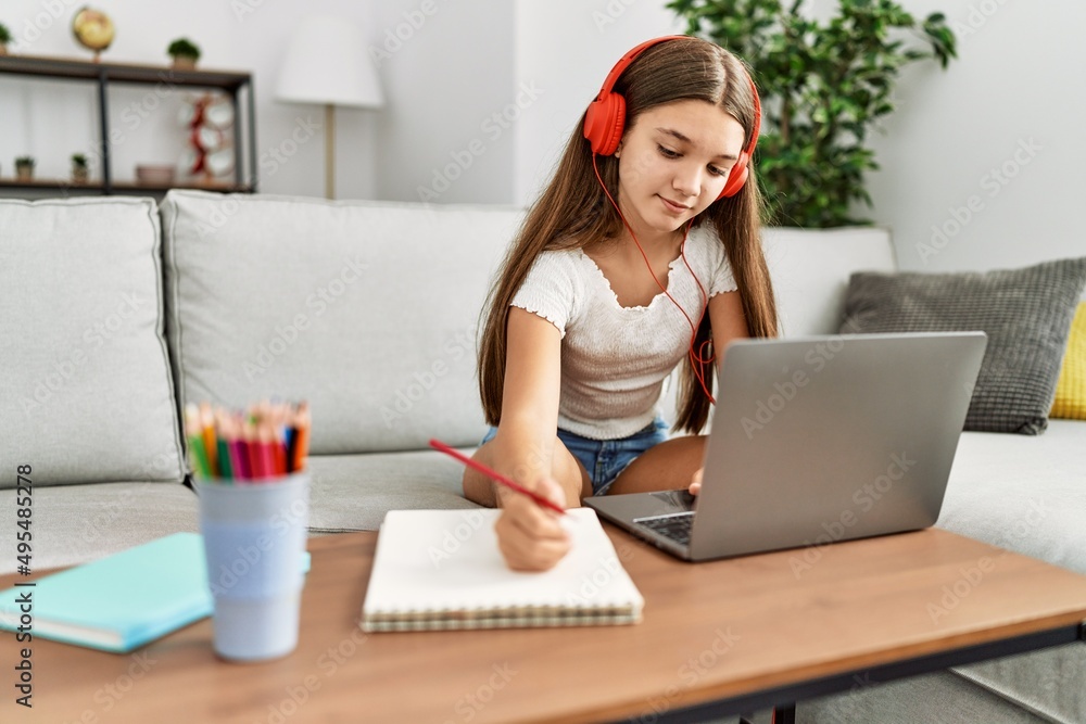 Adorable girl doing homework using laptop at home Adorable girl doing homework using laptop at home