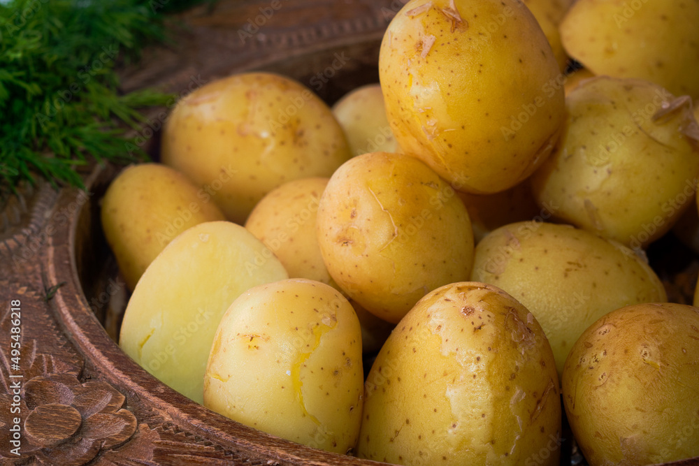Delicious spring dinner - boiled young potatoes with butter and dill served in the wooden bowl Delicious spring dinner - boiled young potatoes with butter and dill served in the wooden bowl