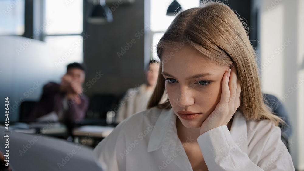 Close-up young caucasian upset girl student sitting alone in classroom at desk suffering from abuse ridicule bad attitude from classmates feels humiliated sad disappointed abandoned lonely offended