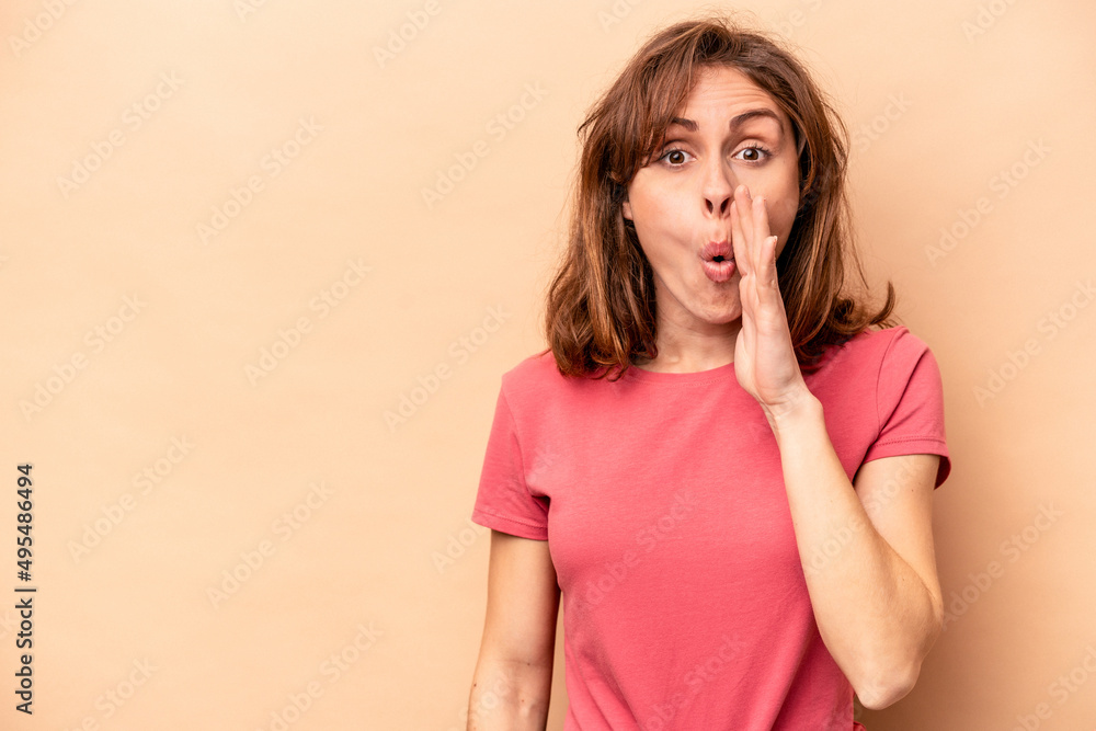 Young caucasian woman isolated on beige background is saying a secret hot braking news and looking aside Young caucasian woman isolated on beige background is saying a secret hot braking news and looking aside