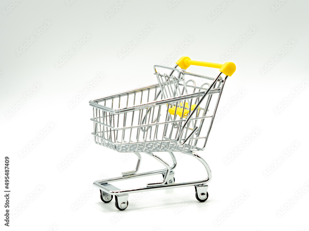 Small empty shopping cart on white and grey background. Selective focus.