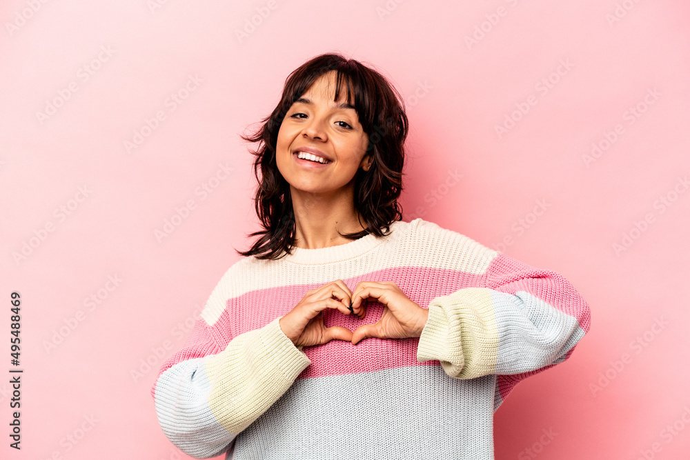 Young hispanic woman isolated on pink background smiling and showing a heart shape with hands. Young hispanic woman isolated on pink background smiling and showing a heart shape with hands.