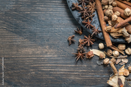 Food, Spices and Ingredent Concept. Flat lay top view of Chinese star anise, Cinnamon and Amomum krervanh with black plate on wooden table with copy space. photo