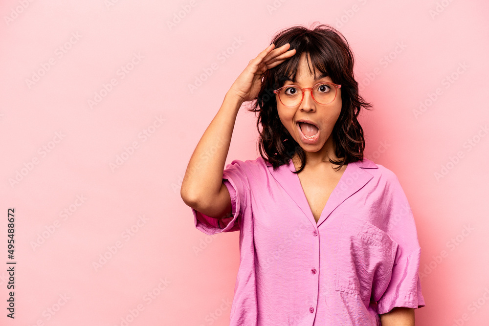 Young hispanic woman isolated on pink background shouts loud, keeps eyes opened and hands tense. Young hispanic woman isolated on pink background shouts loud, keeps eyes opened and hands tense.