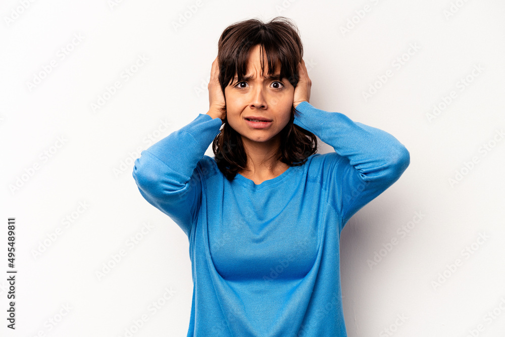 Young hispanic woman isolated on white background covering ears with hands trying not to hear too loud sound. Young hispanic woman isolated on white background covering ears with hands trying not to hear too loud sound.