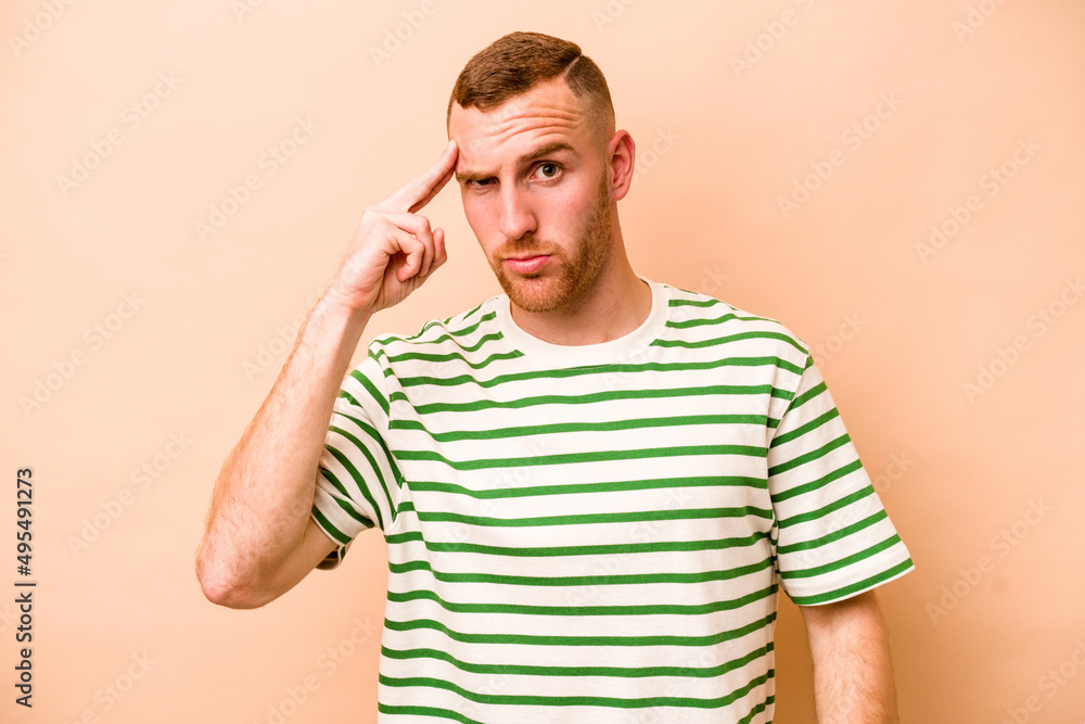 Young caucasian man isolated on beige background pointing temple with finger, thinking, focused on a task. Young caucasian man isolated on beige background pointing temple with finger, thinking, focused on a task.