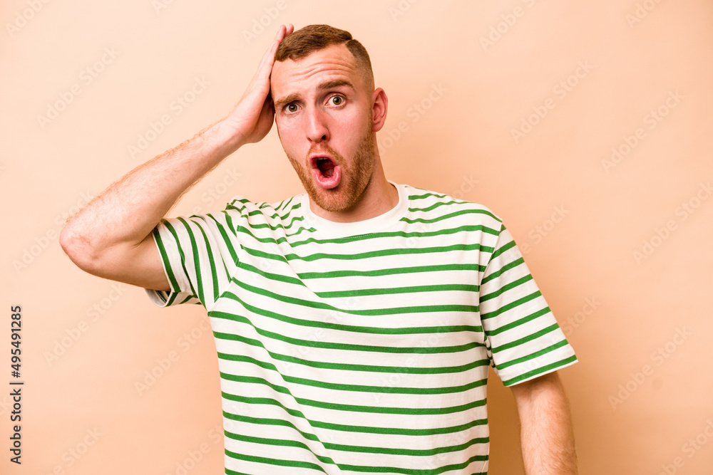 Young caucasian man isolated on beige background being shocked, she has remembered important meeting. Young caucasian man isolated on beige background being shocked, she has remembered important meeting.