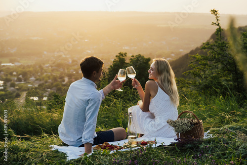 Obraz na płótnie Romantic couple having happy on summer picnic, sitting on the hill, eating and drinking wine. w salonie