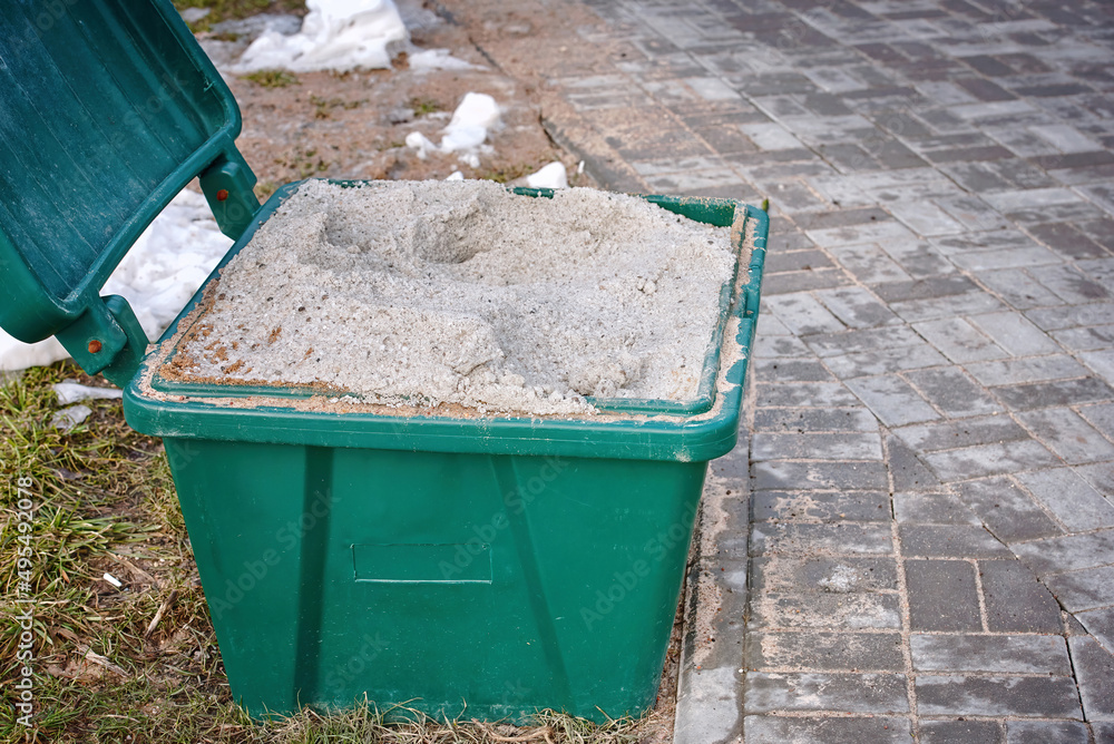 Open salt container, salt and san for slippery surface closeup. Container with rock salt mixture used in cold season to sprinkle sidewalks, ice melt, slippery prevention. Melting snow and ice Open salt container, salt and san for slippery surface closeup. Container with rock salt mixture used in cold season to sprinkle sidewalks, ice melt, slippery prevention. Melting snow and ice