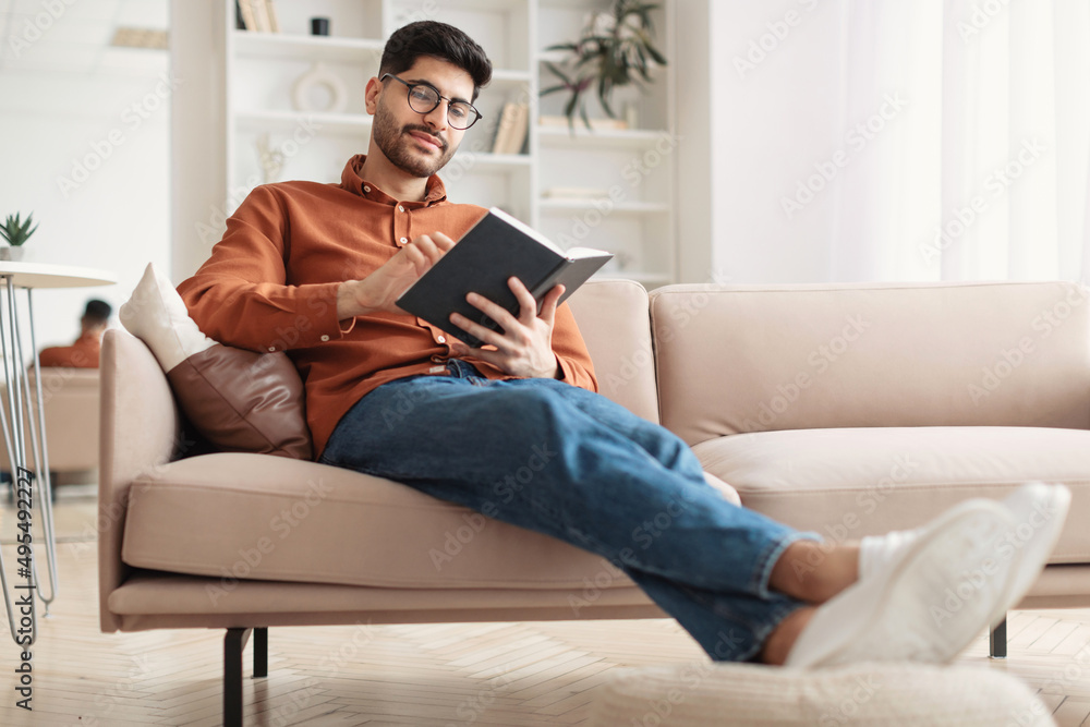 Smiling Arab man in glasses reading paper book Smiling Arab man in glasses reading paper book