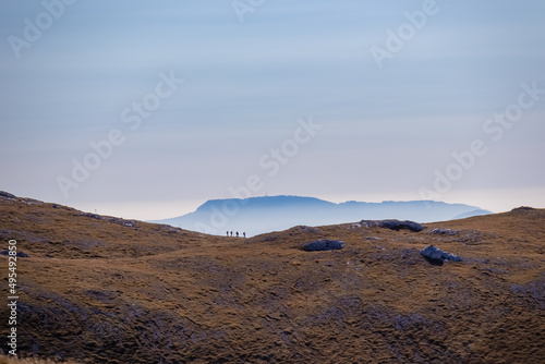 A group of people hiking with a panoramic view on the mountain peaks of the Hochschwab Region in Upper Styria, Austria. Soft hill landscape in the Alps in Europe. Wilderness. Concept freedom, trekking