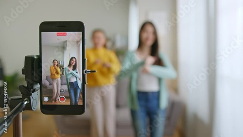 Asian young woman with her friend created her dancing video by smartphone camera together. To share video on tiktok social media application