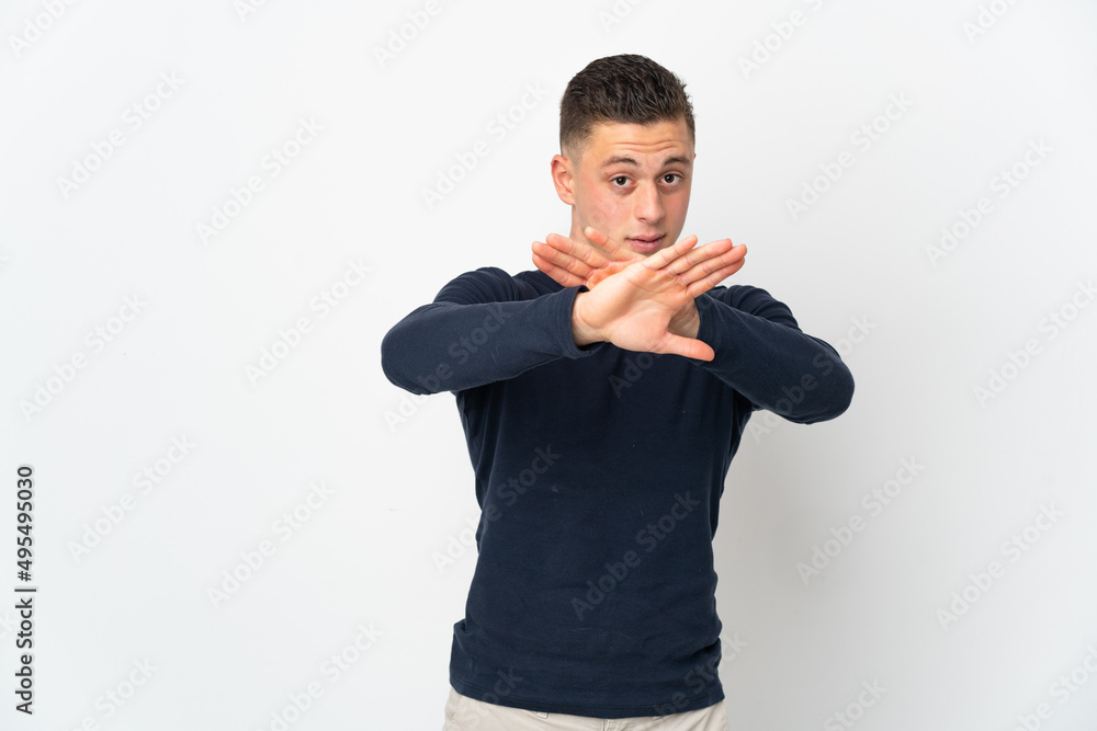 Young caucasian man isolated on white background making stop gesture with her hand to stop an act