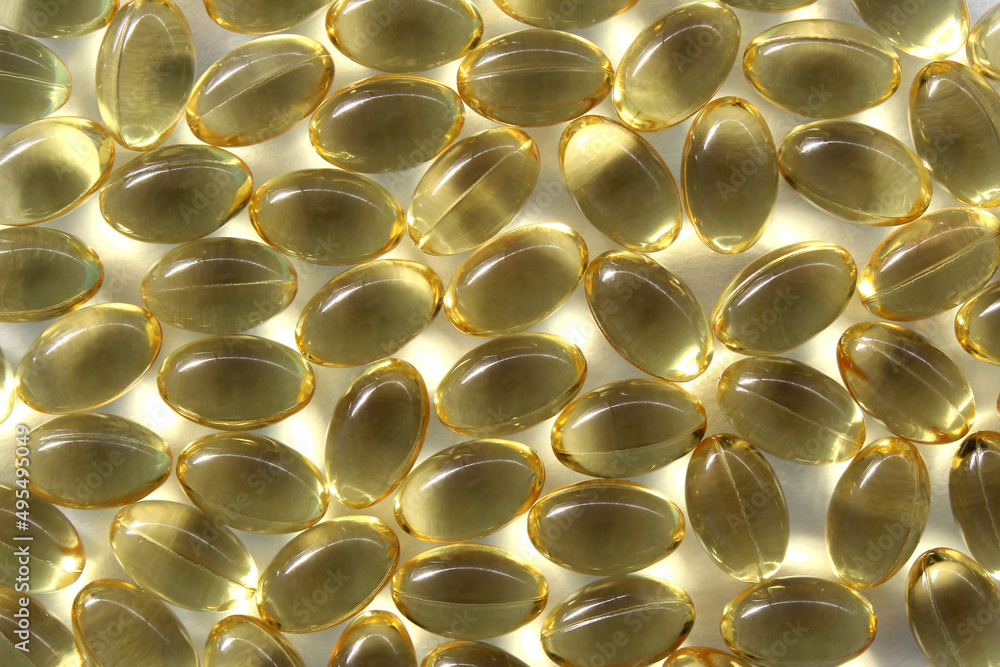 Texture of vitamin capsules of fish oil in golden color.