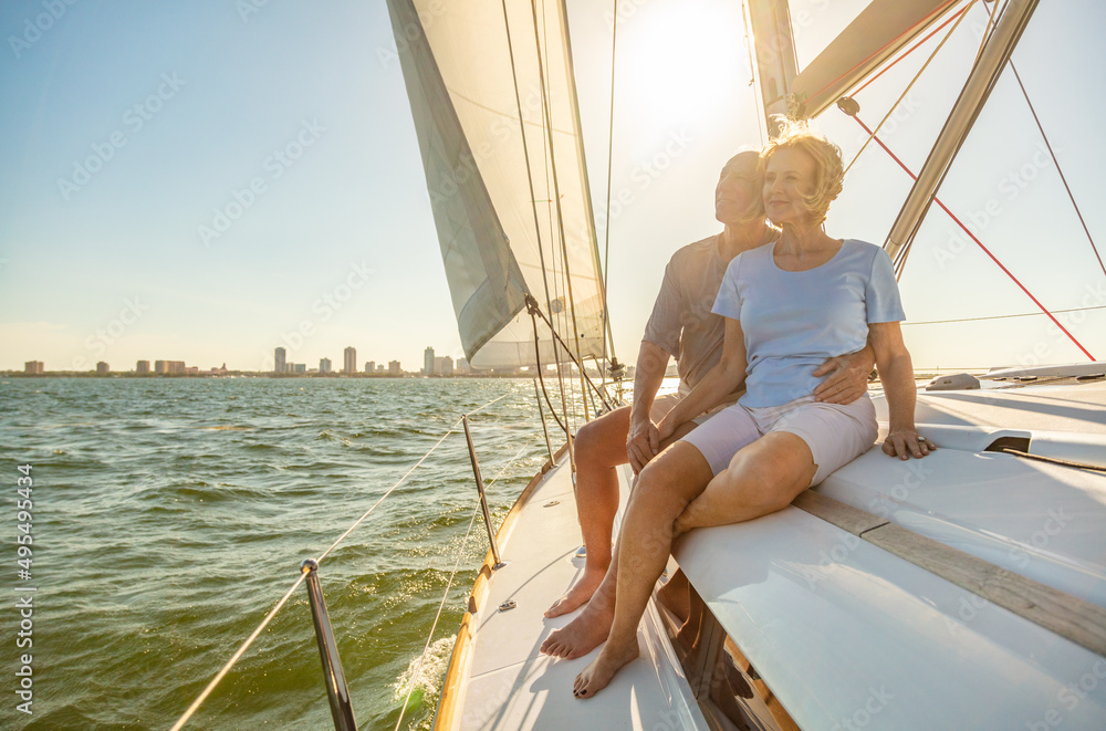 Fototapeta premium Relaxed senior couple sailing private yacht at sunset