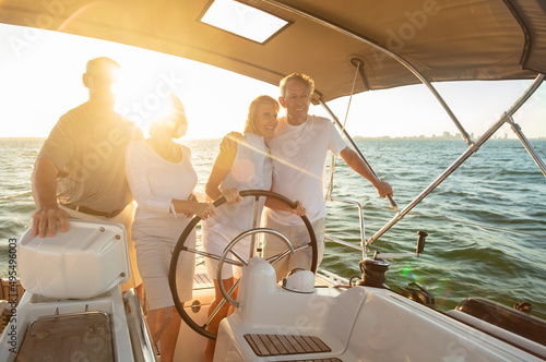 Seniors on vacation steering luxury yacht at sunset © Spotmatik