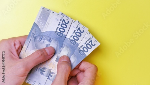 Indonesian Rupiah the official currency of Indonesia. Man's hand is making a payment. Business Saving Income Money Investment Economy and Finance Concept Uang 2000 2.000 Rupiah. Two thousand Rupiah.