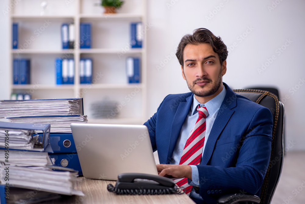 Young male employee and too much work in the office Young male employee and too much work in the office