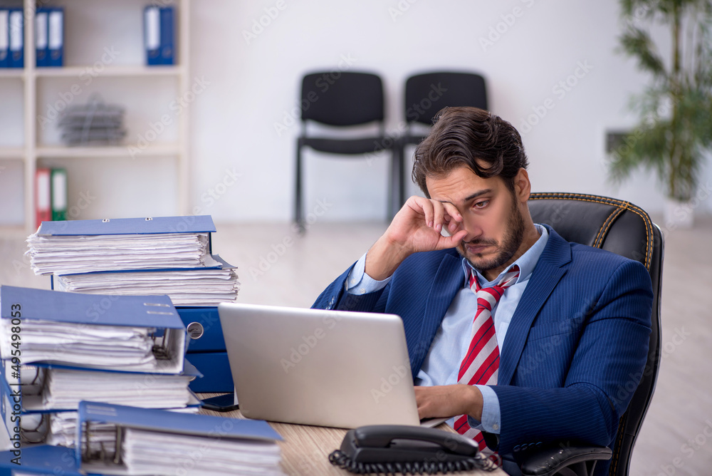 Young male employee and too much work in the office Young male employee and too much work in the office