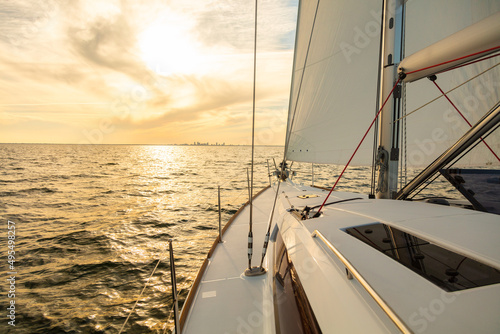Obraz na płótnie Sailing private yacht towards city skyline at sunrise