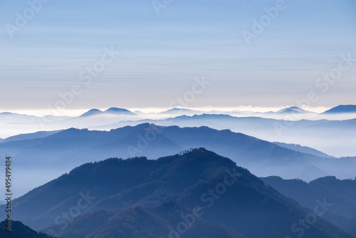 A panoramic view on the mountain peaks of the Hochschwab Region in Upper Styria, Austria. Cloudless weather on a sunny summer day in the Alps. Blue misty valley and soft hills. Concept freedom photo