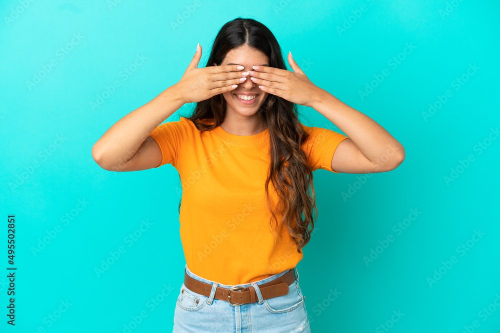 Young caucasian woman isolated on blue background covering eyes by hands and smiling