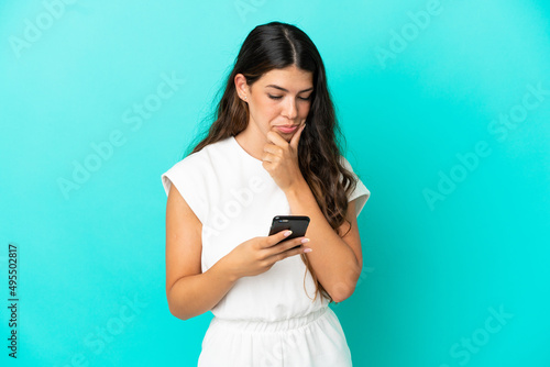Young caucasian woman isolated on blue background thinking and sending a message