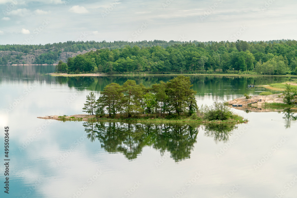 Sweden, Loftahammar, Small island on calm sea trees and clouds