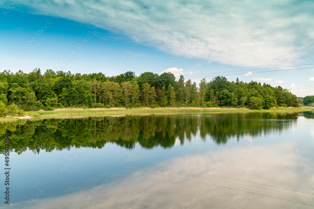 Obraz premium Sweden, Loftahammar, Calm sea surface reflecting trees and clouds
