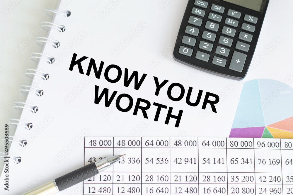 Know Your Worth inscription on a notepad on a table next to a calculator, pen, accounting reports and charts Know Your Worth inscription on a notepad on a table next to a calculator, pen, accounting reports and charts