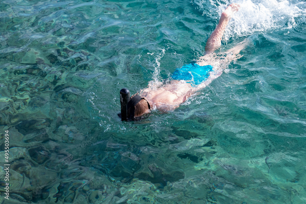 boy in an underwater snorkel swims in the sea