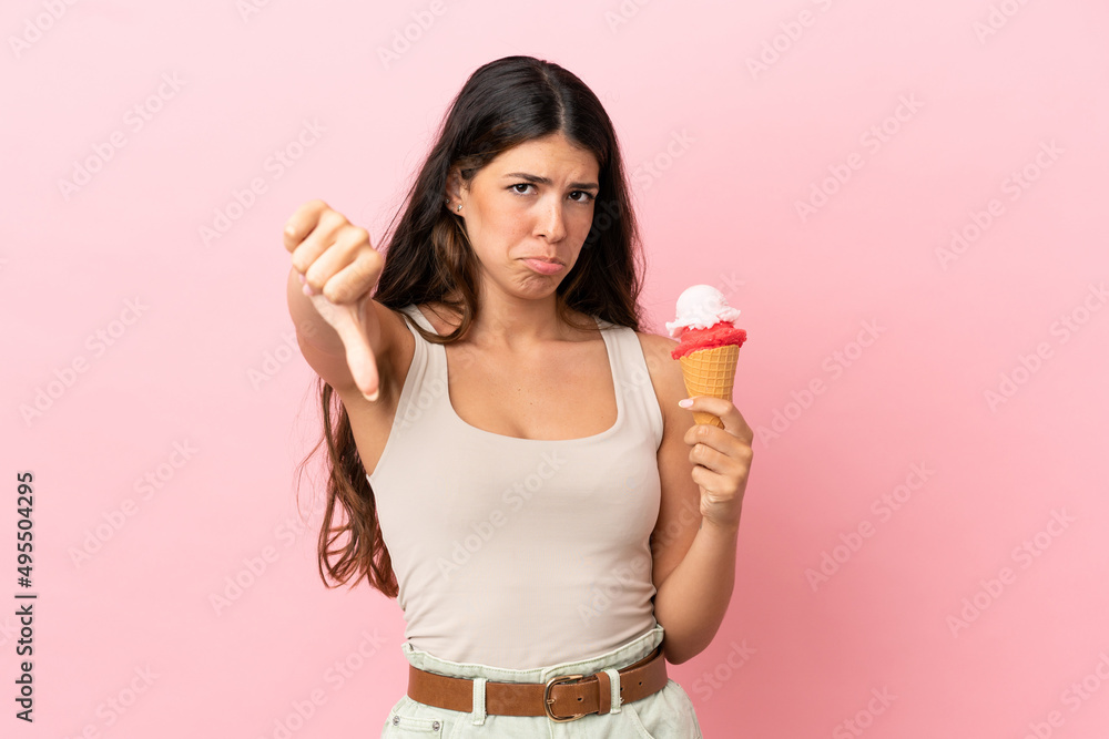 Young caucasian woman with a cornet ice cream isolated on pink background showing thumb down with negative expression Young caucasian woman with a cornet ice cream isolated on pink background showing thumb down with negative expression