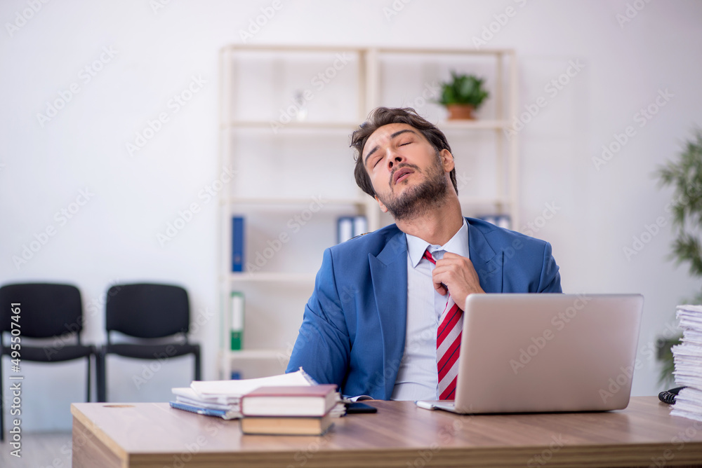Young male employee and too much work in the office Young male employee and too much work in the office