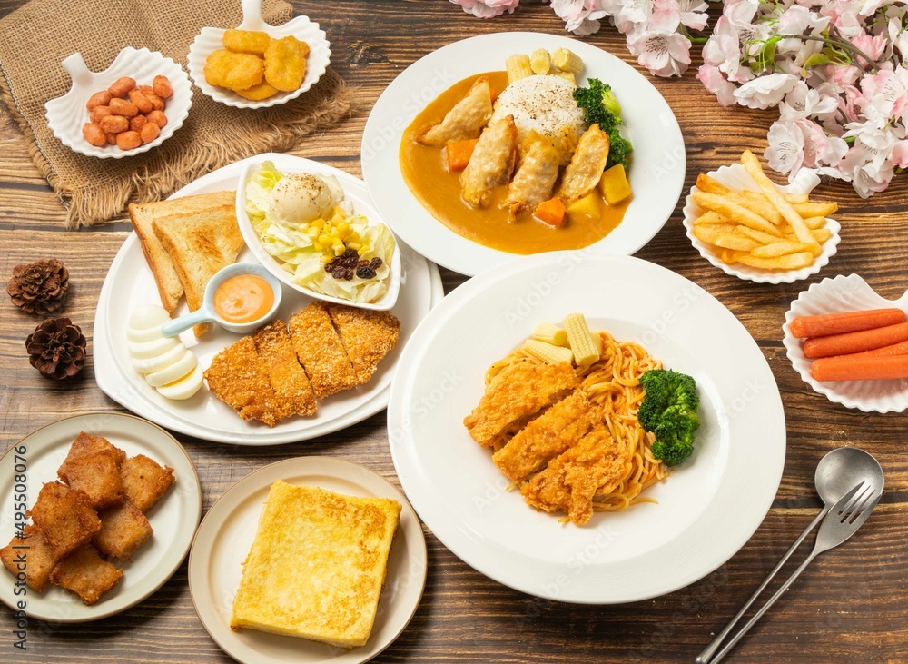 Assorted food French Toast, Fried small bean, chicken thighs, pasta spaghetti, hot dogs, Fried Dumpling, Curry Noodles Chicken Cutlet Platter, turnip cake, in dish side view on wooden table Assorted food French Toast, Fried small bean, chicken thighs, pasta spaghetti, hot dogs, Fried Dumpling, Curry Noodles Chicken Cutlet Platter, turnip cake, in dish side view on wooden table