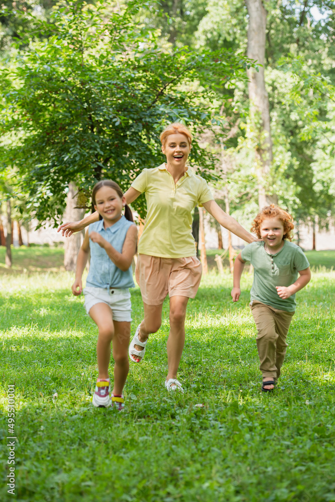 full length view of excited children with mother running in summer park.