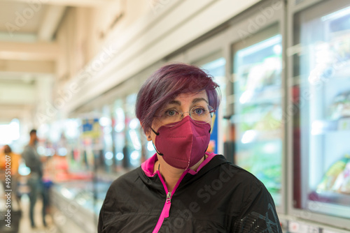 Portrait of a woman shopping in a supermarket, wearing a protective mask for covid.