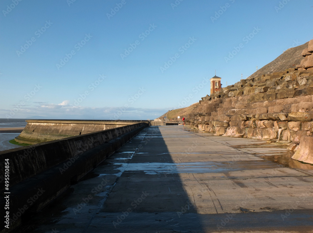 concrete stairs on seawall in the cliffs area blackpool with the beach at low tide in sunlight with the old boat pool and tower in the difference