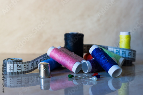 Set of thread spools of various colors with pins, thimble and tape measure