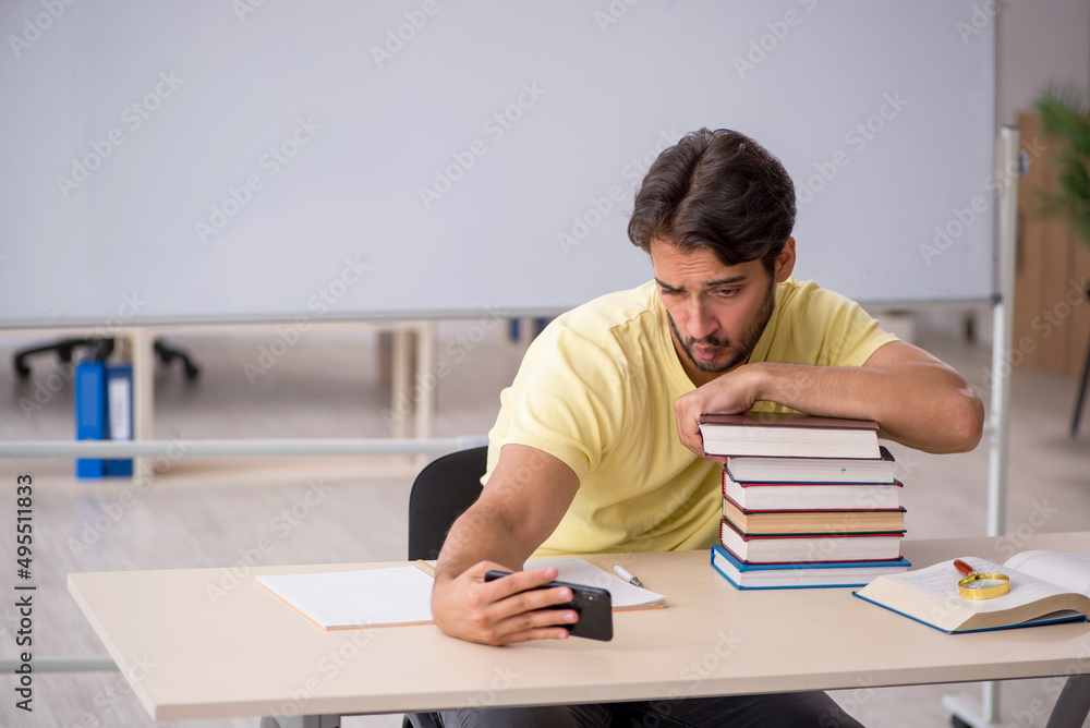 Young male student preparing for exams in the classroom