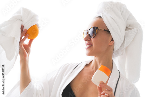 Girl holding a cosmetic cream and looking at an orange