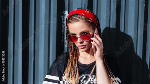 young hipster woman with bandana and braids talking on the phonesmart on sunny summer day outdoor. Banner photo