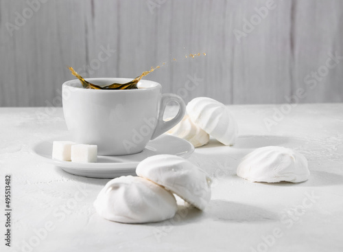 Fresh black coffee in a white cup. Marshmallows on the table