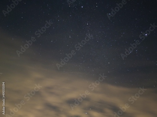Blue-pink starry sky with clouds. The dark blue night sky, on which the stars shine, in the sky there are small light cumulus clouds. Stars of different sizes and brightness.