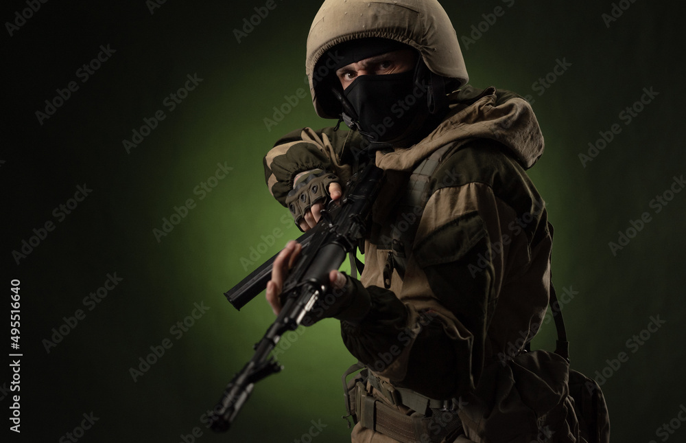 a Russian soldier in a helmet in military clothes with a Kalashnikov assault rifle on a dark background in the studio a Russian soldier in a helmet in military clothes with a Kalashnikov assault rifle on a dark background in the studio