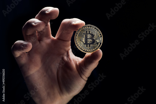 A businessman's hand holds a golden bitcoin and close-up of a hand with a coin. The concept of digital cryptocurrency, stock trading and the market.